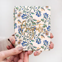 Hand holding a floral notebook with 'Congratulations' text on a light background