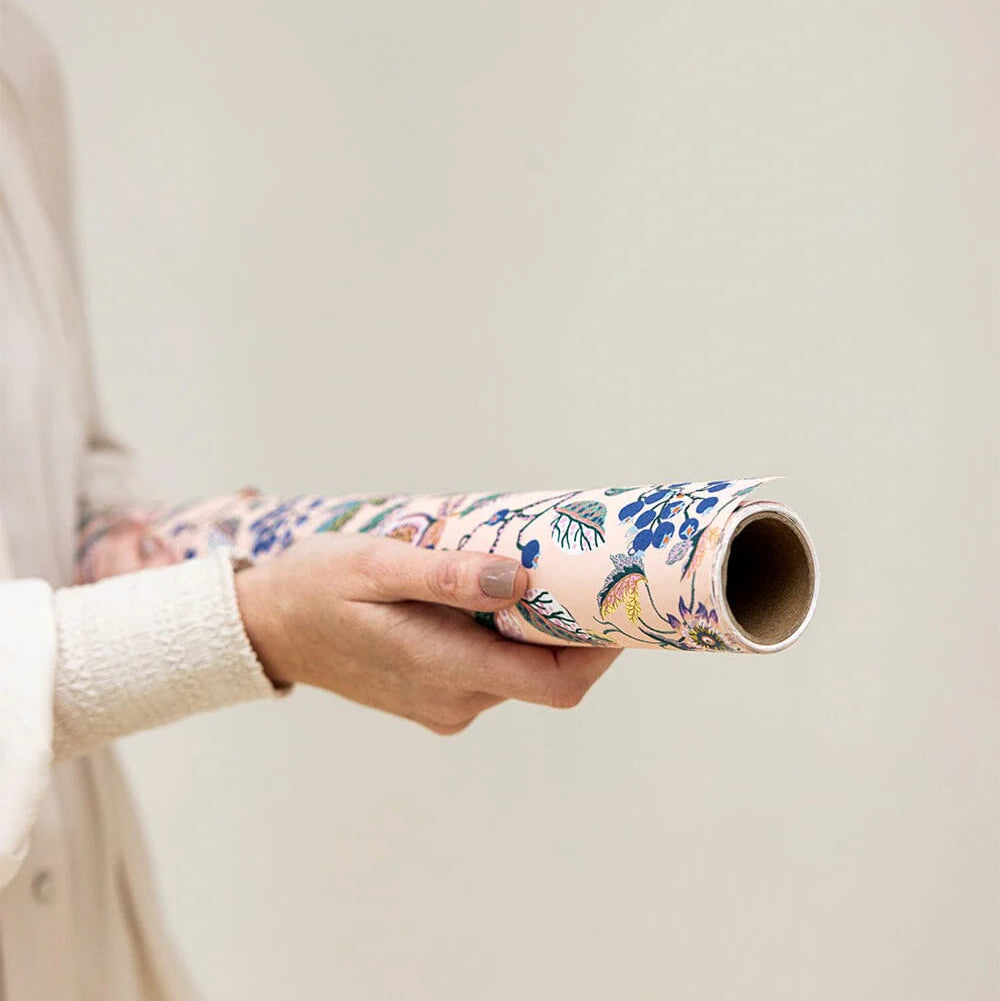 Person holding a floral-patterned roll of paper against a plain background