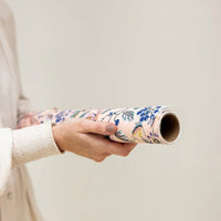 Person holding a floral-patterned roll of paper against a plain background