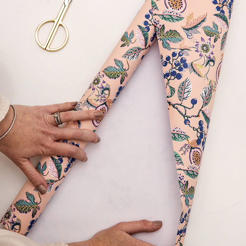 Floral-patterned leggings being held by a person on a white background