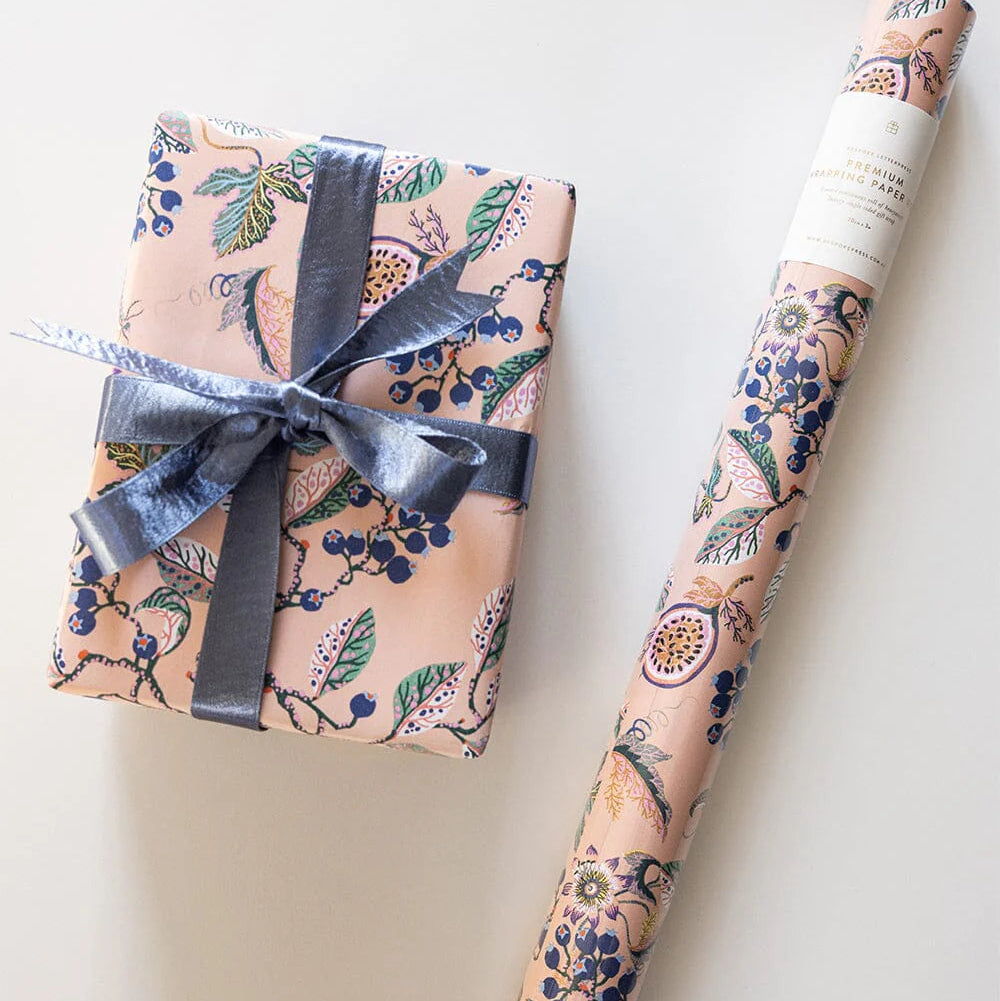 Gift wrapped in floral paper with a roll of matching wrapping paper on a white background